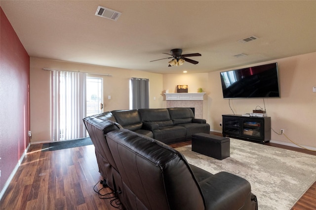 living room featuring a ceiling fan, dark wood finished floors, a fireplace, and visible vents