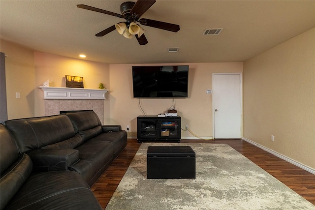living area with visible vents, a tile fireplace, baseboards, ceiling fan, and dark wood-style floors
