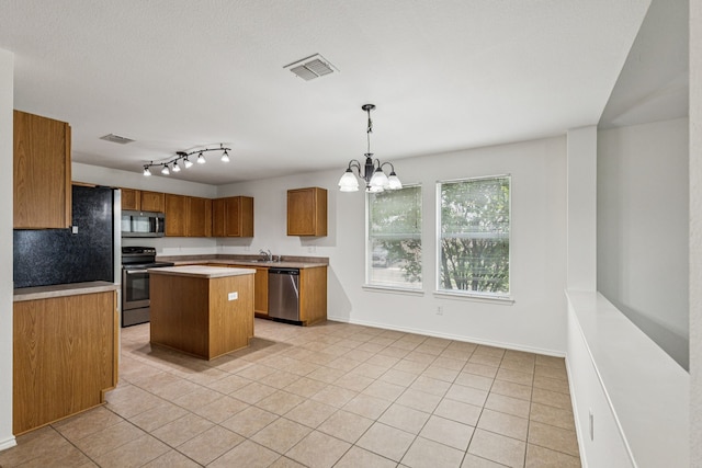 1416 Eagles Nest Trl, Krum, TX 76249 - kitchen with stainless steel appliances, brown cabinets, a sink, a kitchen island, and a chandelier