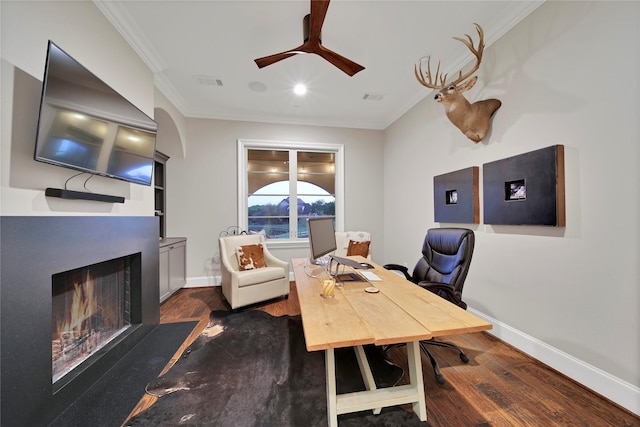 office space with a lit fireplace, visible vents, ornamental molding, and dark wood finished floors