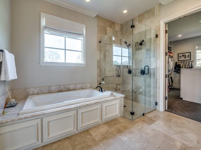 full bathroom featuring a spacious closet, a shower stall, a bath, and a wealth of natural light
