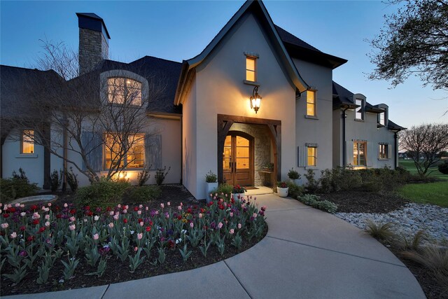 entrance to property featuring a chimney and stucco siding