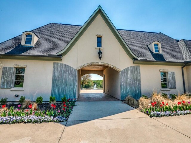 exterior space with roof with shingles and stucco siding