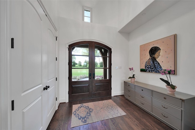 foyer entrance featuring french doors, arched walkways, baseboards, a high ceiling, and dark wood-type flooring