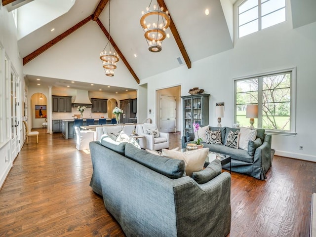living area with plenty of natural light, dark wood finished floors, a notable chandelier, and high vaulted ceiling