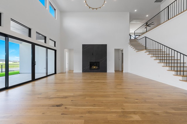 12479 Palmer Dr, Fort Worth, TX 76179 - unfurnished living room with a towering ceiling, stairway, wood finished floors, and a fireplace