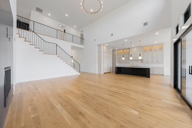 12479 Palmer Dr, Fort Worth, TX 76179 - unfurnished living room with a high ceiling, a sink, light wood-type flooring, and stairs