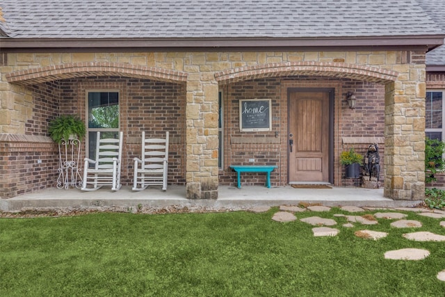 property entrance with a yard, brick siding, and a shingled roof