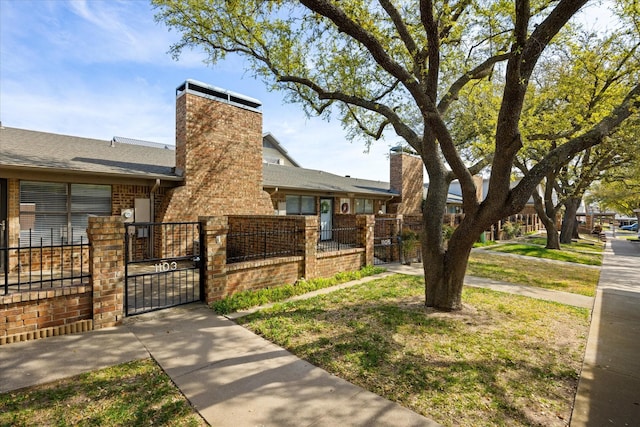 view of home's exterior with brick siding, a gate, a fenced front yard, and a chimney