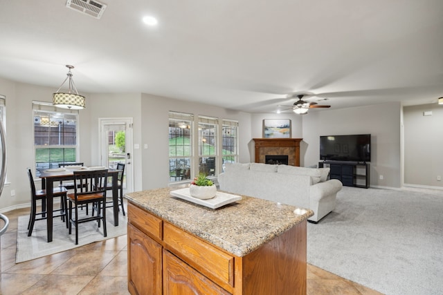 8312 Rancho De La Osa Trl, Mckinney, TX 75070 - kitchen with ceiling fan, a center island, a tiled fireplace, hanging light fixtures, and light tile patterned floors