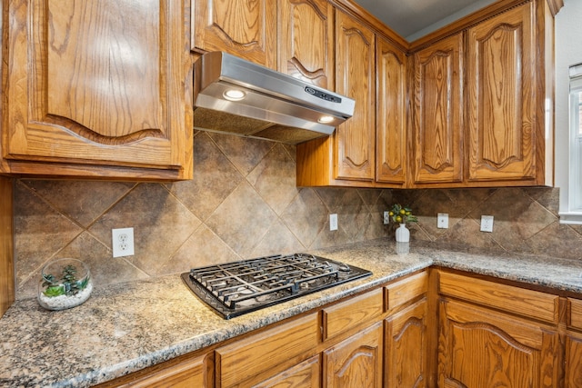 8312 Rancho De La Osa Trl, Mckinney, TX 75070 - kitchen featuring under cabinet range hood, brown cabinets, black gas stovetop, and backsplash
