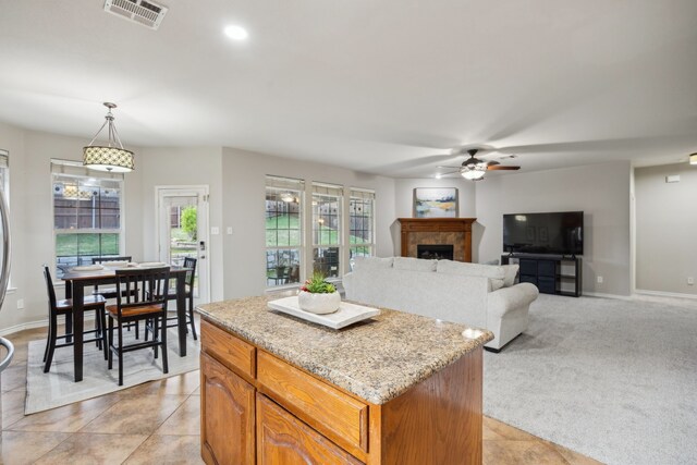 8312 Rancho De La Osa Trl, Mckinney, TX 75070 - kitchen featuring ceiling fan, a center island, a tile fireplace, hanging light fixtures, and baseboards