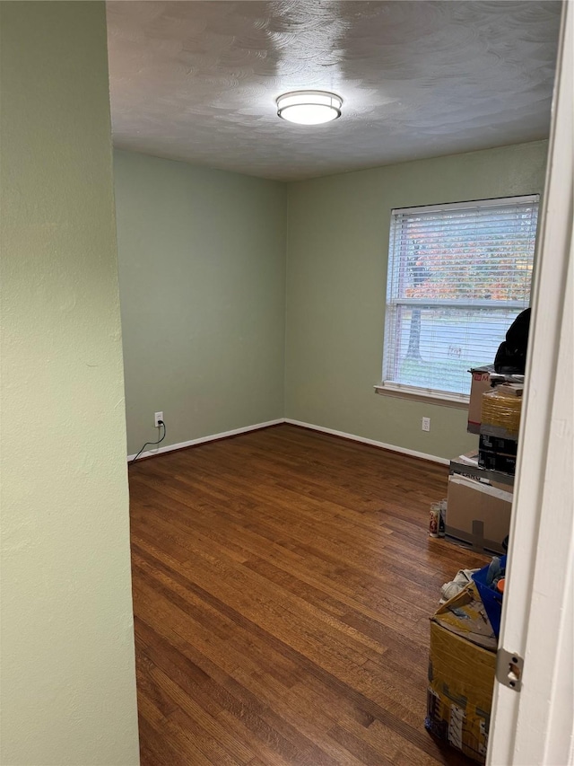 empty room with baseboards and wood finished floors