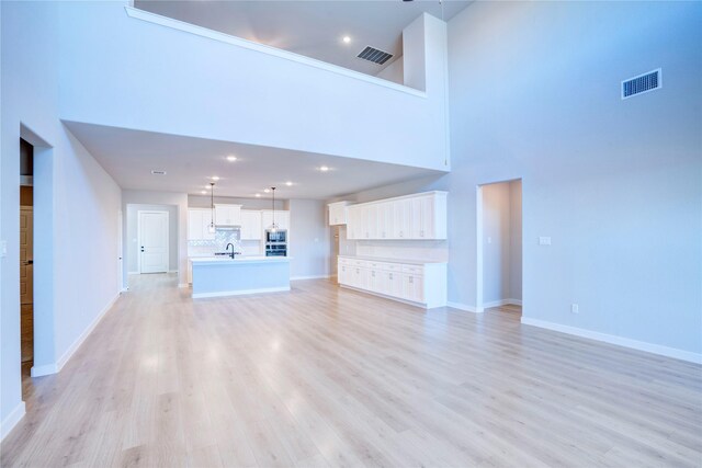 1208 Arcadia Ln, Northlake, TX 76226 - unfurnished living room featuring a sink, light wood-type flooring, baseboards, a towering ceiling, and recessed lighting