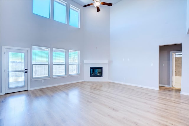 1208 Arcadia Ln, Northlake, TX 76226 - unfurnished living room with a high ceiling, ceiling fan, healthy amount of natural light, light wood-style floors, and a glass covered fireplace