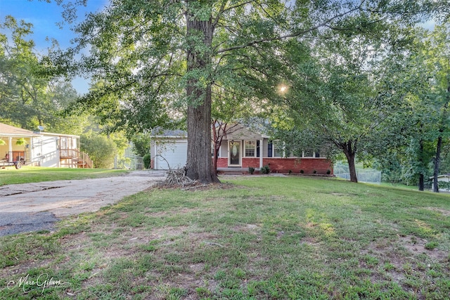 view of front of home featuring brick siding, a front yard, driveway, and a garage