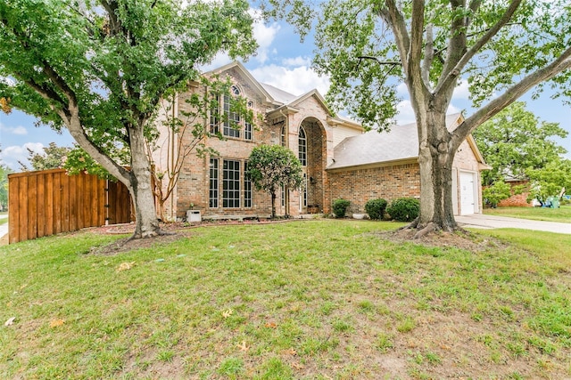traditional-style house with brick siding, a garage, and a front lawn