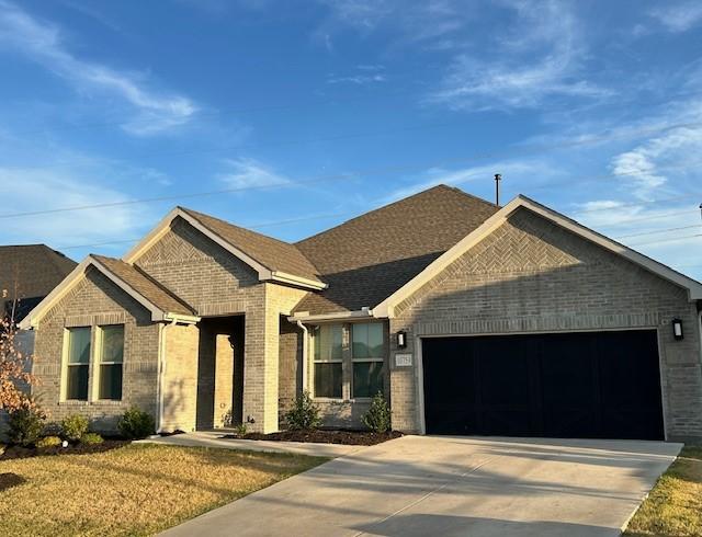 view of front of home with brick siding, driveway, and a garage