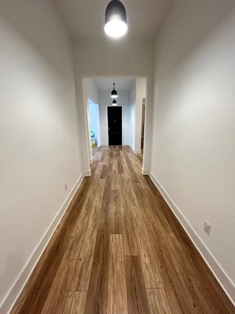 corridor featuring baseboards and dark wood finished floors