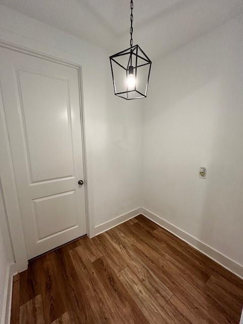 unfurnished dining area with baseboards and dark wood finished floors