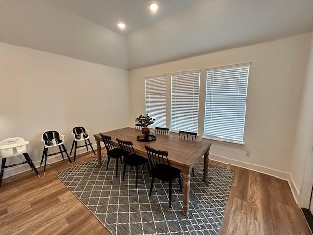 dining space featuring baseboards, vaulted ceiling, wood finished floors, and recessed lighting