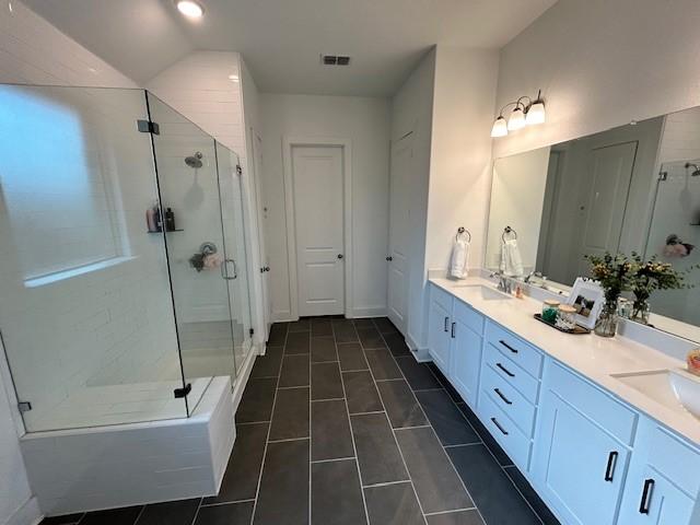 bathroom with double vanity, a sink, a shower stall, and visible vents