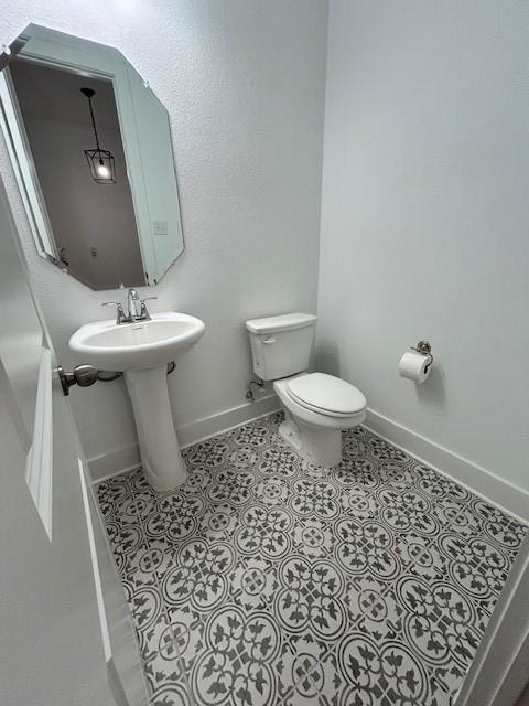 bathroom with baseboards, toilet, tile patterned flooring, and a sink