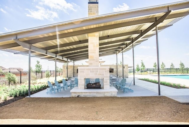 view of patio / terrace with an outdoor stone fireplace and fence
