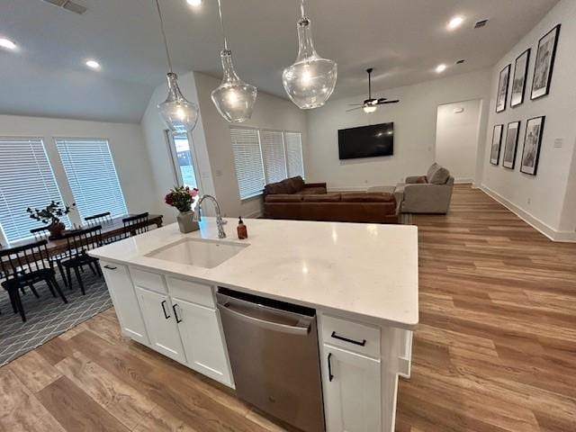kitchen with an island with sink, a sink, a ceiling fan, wood finished floors, and stainless steel dishwasher