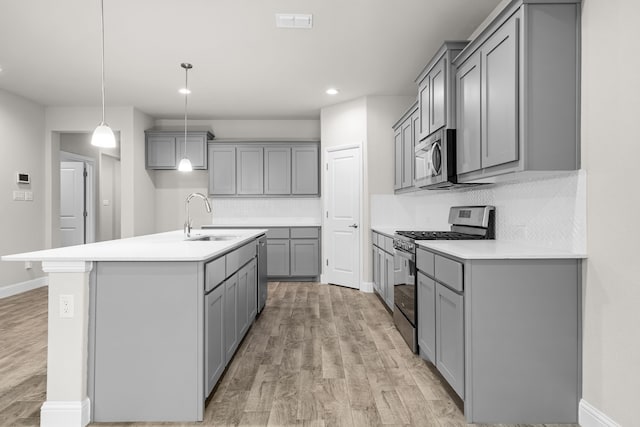 825 Blackhorse Trl, Fort Worth, TX 76247 - kitchen featuring appliances with stainless steel finishes, gray cabinetry, a sink, light wood finished floors, and backsplash
