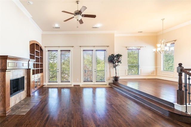 unfurnished living room with a tiled fireplace, dark wood-style floors, ceiling fan with notable chandelier, visible vents, and ornamental molding