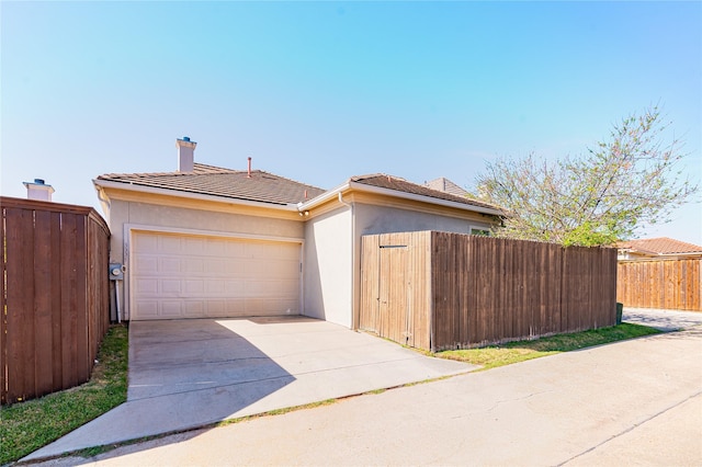 view of front of property with a tile roof, concrete driveway, stucco siding, fence, and a garage