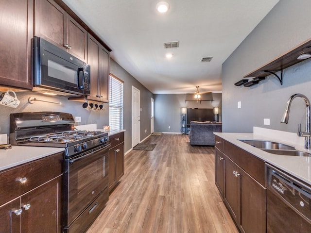 kitchen featuring light wood-type flooring, a sink, black appliances, and visible vents