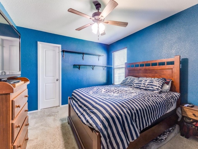 bedroom with light carpet, baseboards, a textured wall, and a ceiling fan