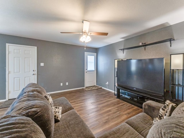 living area with baseboards, wood finished floors, and a ceiling fan
