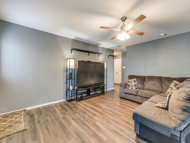 living area featuring wood finished floors, baseboards, and ceiling fan