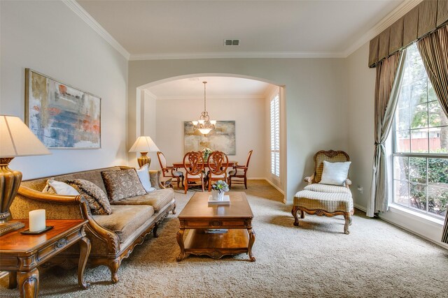 carpeted living area with visible vents, arched walkways, baseboards, an inviting chandelier, and ornamental molding