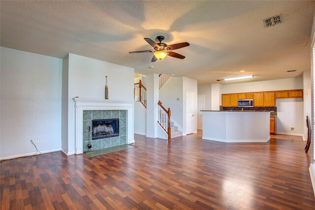 3331 Midstream Ct, Mesquite, TX 75181 - unfurnished living room with dark wood finished floors, stairs, a fireplace, a ceiling fan, and a textured ceiling