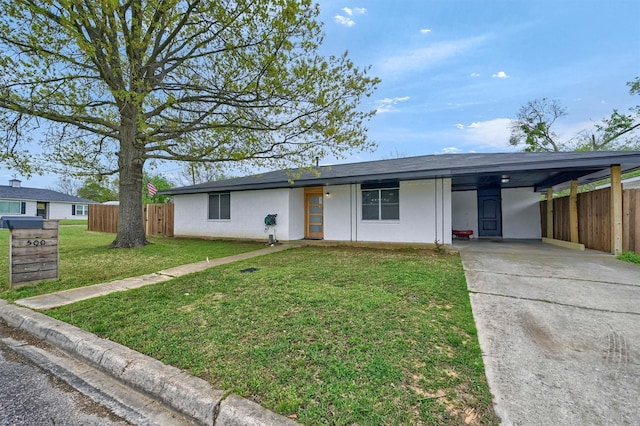 view of front of house with concrete driveway, stucco siding, fence, a front yard, and an attached carport