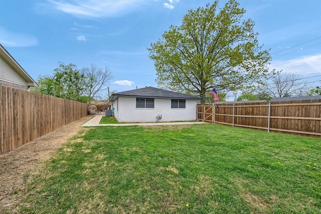 rear view of property with a fenced backyard and a yard