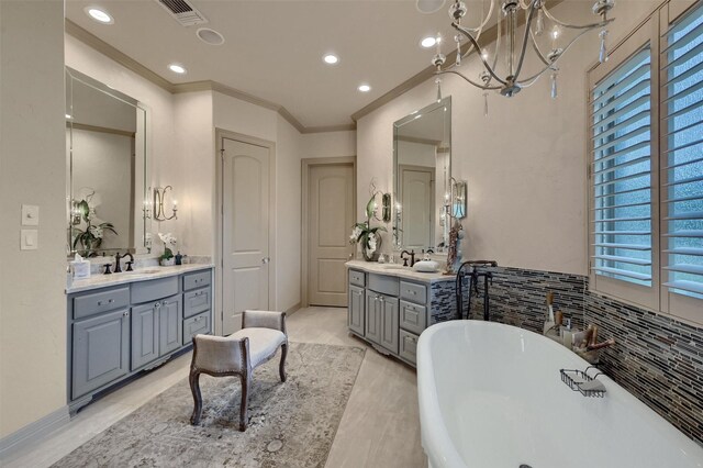 7545 Colton Ln, Pilot Point, TX 76258 - bathroom with two vanities, a freestanding bath, ornamental molding, a chandelier, and recessed lighting