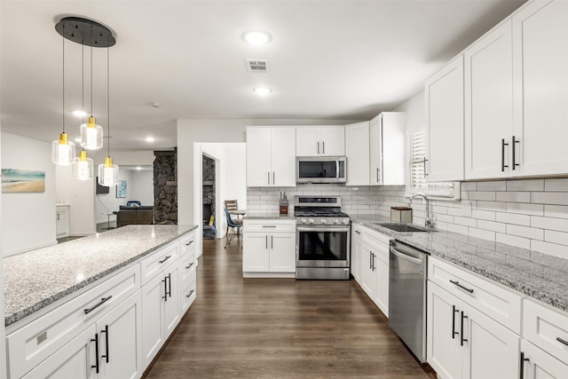 1018 Brookhollow Dr, Irving, TX 75061 - kitchen featuring stainless steel appliances, a sink, tasteful backsplash, dark wood finished floors, and white cabinets