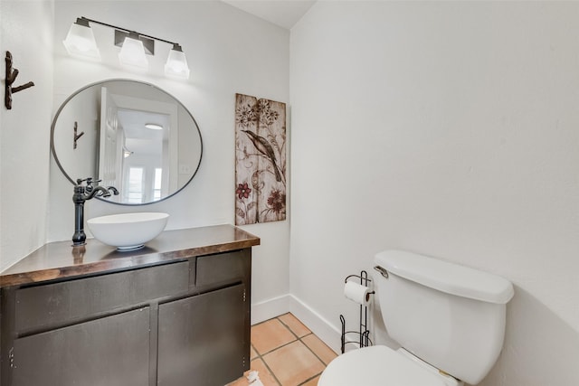 bathroom with tile patterned floors, toilet, baseboards, and vanity