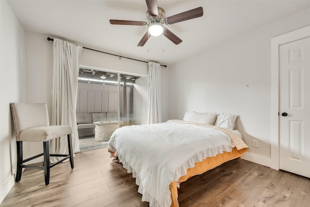 bedroom featuring a ceiling fan, baseboards, and wood finished floors