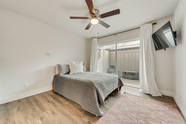 bedroom with a ceiling fan, baseboards, access to outside, and wood finished floors