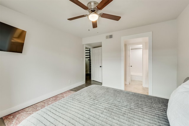 bedroom featuring baseboards, ensuite bathroom, visible vents, and a ceiling fan