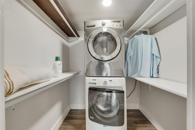 clothes washing area featuring wood finished floors, baseboards, laundry area, and stacked washer / drying machine