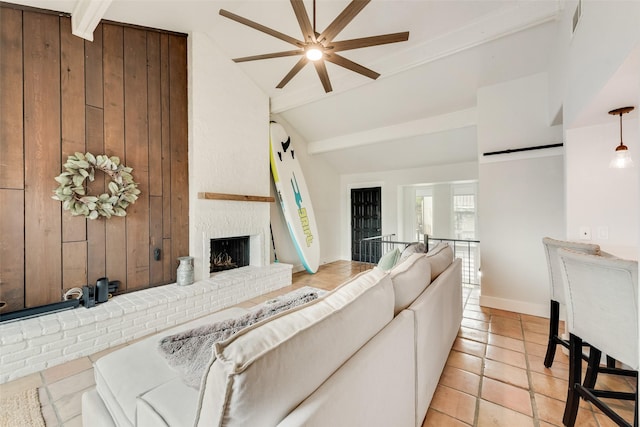 living room featuring a brick fireplace, wood walls, a ceiling fan, and beam ceiling