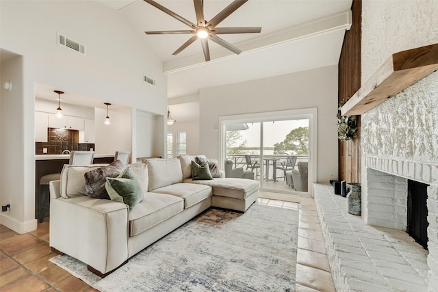 living area featuring a fireplace, high vaulted ceiling, ceiling fan, and visible vents