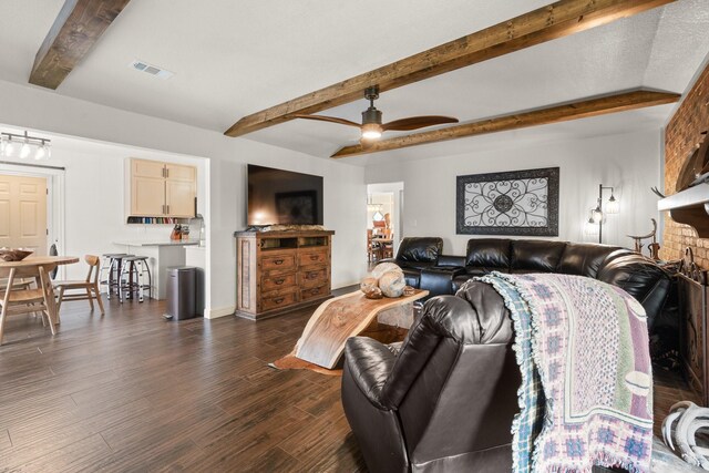 living area with a ceiling fan, dark wood-style floors, beamed ceiling, baseboards, and visible vents